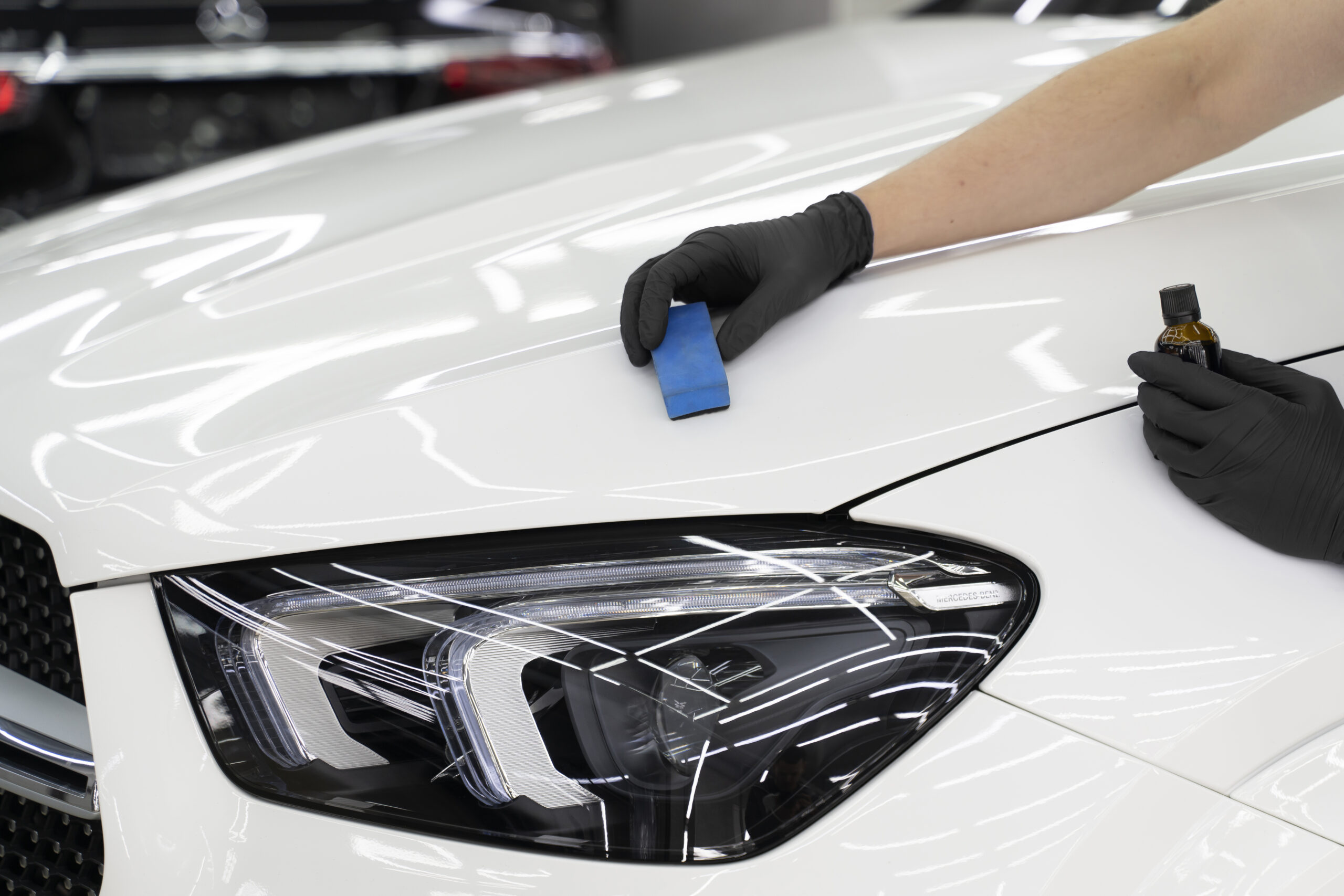 Expert applying ceramic coating for a glossy, durable finish on a car surface.